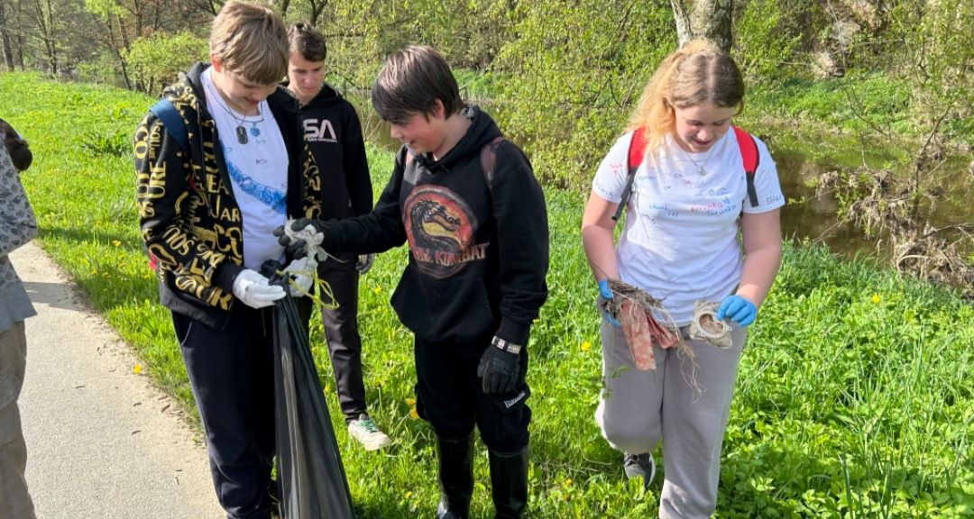 žáci sbírají u řeky odpadky